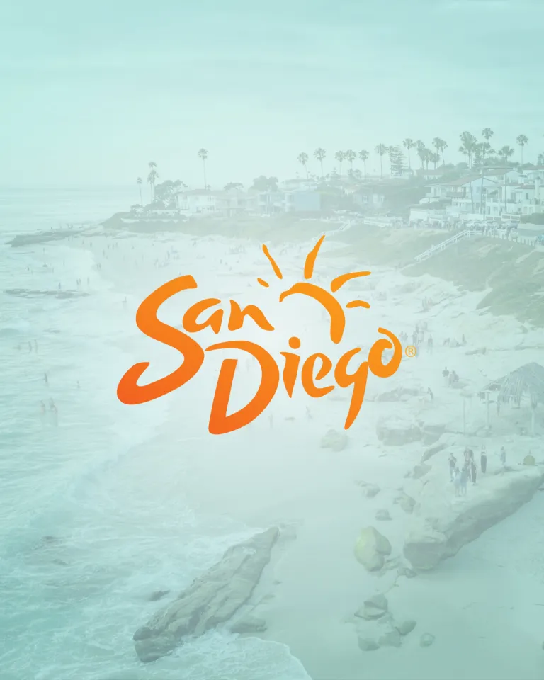A beach scene with people by the ocean and houses on the cliffs, overlaid with the orange "San Diego" logo featuring a sun graphic.