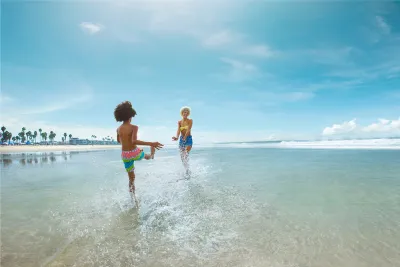 Mother and son splashing on the wide open sands of a San Diego beach on a sunny day