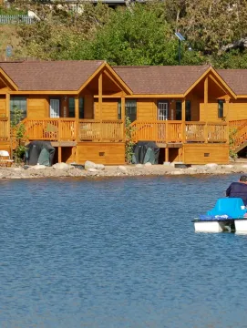 Lakefront cabins overlooking Santee lakes as a father daughter fish off of a pontoon boat